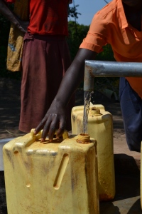 Borehole user fetching water in Dokolo